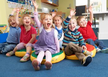 Group Of Pre School Children Answering Question In Classroom